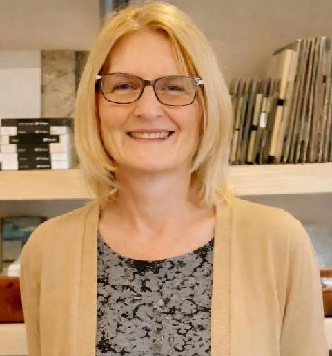 Smiling woman with glasses in office setting.