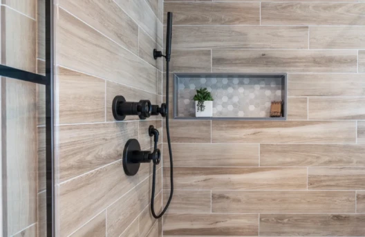 Modern shower area with built-in shelf and black fixtures.