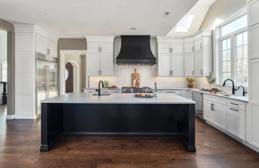 Modern kitchen with island and white cabinets.