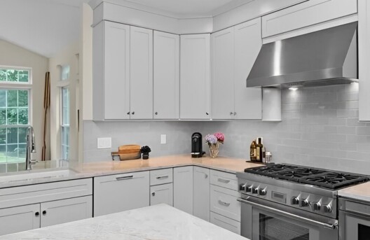 Modern kitchen with white cabinets and stove.