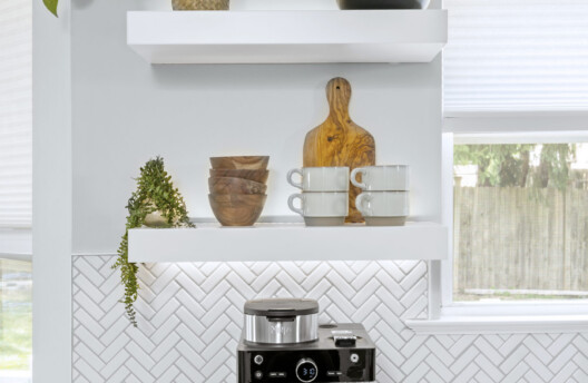 Bright Kitchen Remodel With White Shaker Cabinets, Navy Blue Island, Herringbone Tile Backsplash, Stainless Steel Range Hood, Under-Counter Wine Fridge and Open Shelving