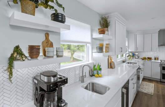 Bright Kitchen Remodel With White Shaker Cabinets, Navy Blue Island, Herringbone Tile Backsplash, Stainless Steel Range Hood, Under-Counter Wine Fridge and Open Shelving