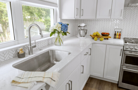 Bright Kitchen Remodel With White Shaker Cabinets, Navy Blue Island, Herringbone Tile Backsplash, Stainless Steel Range Hood, Under-Counter Wine Fridge and Open Shelving