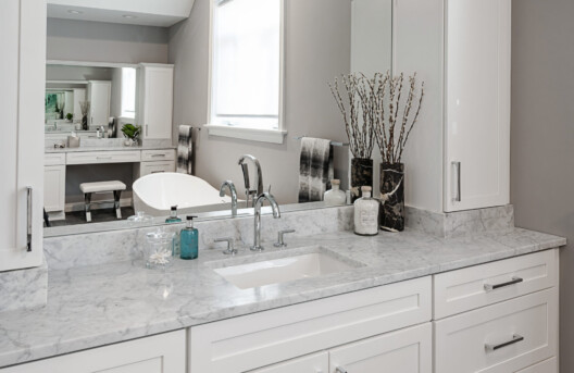 Primary Bathroom Remodel in Lower Gwynned Township, Ambler, PA. Features 4" x 12" Honed White Carrara Marble In The Shower With Full Back-Wall Shelf, Freestanding Tub, Dual Vanities with Marble Tops, Glass Shower Enclosure, and Custom White Cabinetry and Built-In Bench